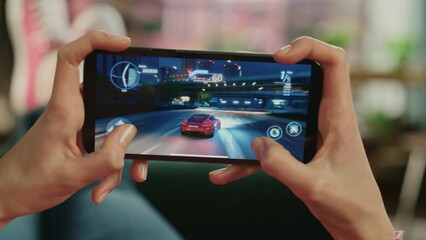 Wall Mural - Female is Relaxing on a Couch at Home, Playing an Interactive Racing Drift Video Game on Her Smartphone. Gamer Lies on a Sofa in Living Room. Close Up POV Footage of Mobile Device Screen.