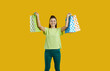 © Studio Romantic - Happy beautiful young girl in casual outfit standing isolated on bright yellow background, smiling and showing shopping bags with many purchases. Cheerful attractive woman enjoying holiday season sale
