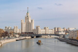 Fototapeta Londyn - Panoramic view of Kotelnicheskaya Embankment Building from Zaryadye park. People on Floating bridge over Moskva River.