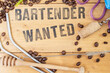 © Dorin - Bartender wanted, written on wooden boards surrounded by coffee beans and bar utensils. Recruitment rustic sign.