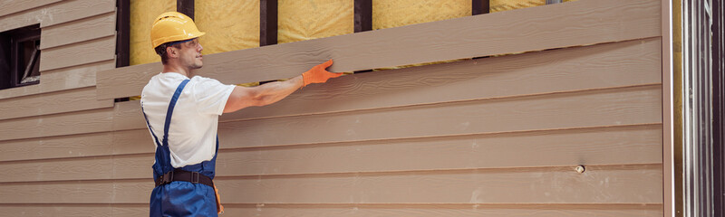 Wall Mural - Handsome man builder building cabin at construction site