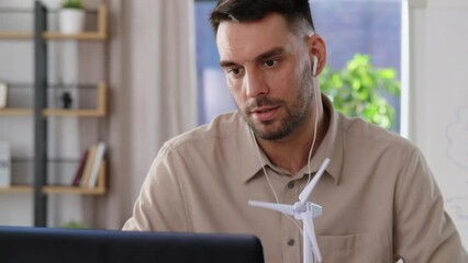 Sticker - distance education, school and green energy concept - male teacher with laptop and wind turbine model having online class at home office