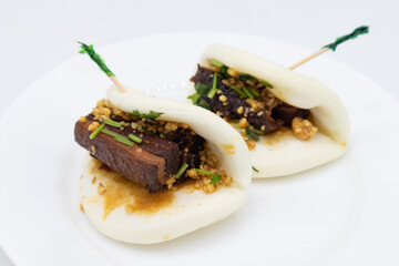 Two Chinese Style Pork Belly Bao Buns on a White Plate