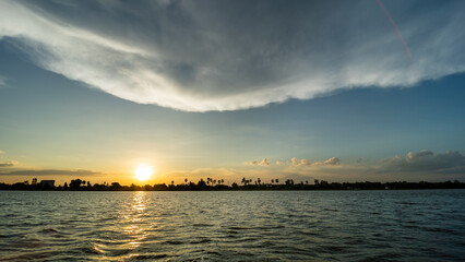 Wall Mural - The atmosphere of sunset over the river, the clouds, and the light of the sun is breathtaking.