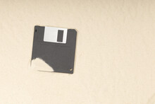 An Old Black Floppy Disk Covered With Sand Is Among The Sand