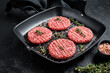 Raw Ground beef meat Burger steak cutlets in grill skillet ready for cooking. Black background. Top view