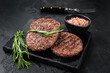 Beef burger patty cutlet for hamburger grilled on BBQ on marble board with rosemary. Black background. Top view