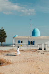 Wall Mural - beautiful woman in white dress near old greece church