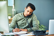 © K Seisa/peopleimages.com - He is constantly busy dealing with clients. Shot of a focused young businessman seated at his desk while taking on the phone and making notes inside the office.