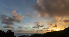 Sunset With Clouds Cause A Radius At The Edge The Calm Ocean With The Bushes In Front Of The Right Hand Side