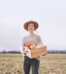 woman with local organic food on agricultural field area. customer or farmer with wooden box of vege