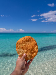 Johnnys cake or yaniqueque, a fry bread made in the Dominican Republic, in the background a virgin beach