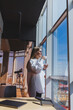 © DSMT - Portrait of a cheerful woman in classic glasses smiling in her free time in a cafe with coffee, positive jewish woman in a white shirt, desk with laptop, remote work