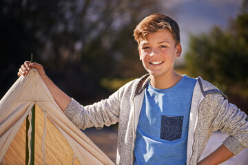 Camping is the best. Shot of a young boy putting up his tent on a camping trip.