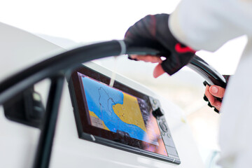 close-up of female hands at the helm of a yacht against the background of an echo sounder