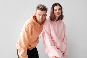 Wall Mural - Cool young couple in hoodies on light background