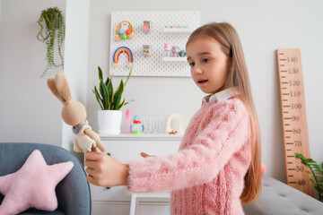 Wall Mural - Cute little girl with toy bunny at home