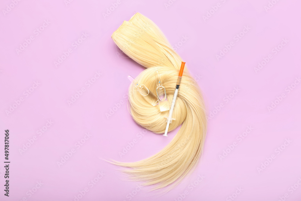 Blonde hair with ampules and syringe on color background
