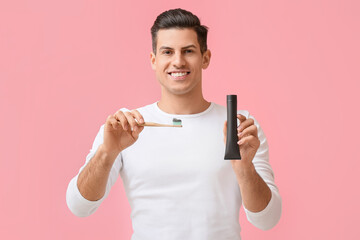 Sticker - Handsome young man with activated charcoal tooth paste and brush on pink background