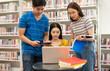 © PK Studio - Happy young university students studying with books in library.