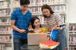 © PK Studio - Happy young university students studying with books in library.
