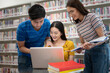 © PK Studio - Happy young university students studying with books in library.