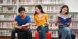 © PK Studio - Happy young university students studying with books in library.