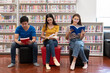 © PK Studio - Happy young university students studying with books in library.