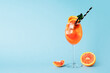 Aperol spritz in glass with slice of orange on blue background