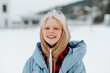 © bodnarphoto - Happy teen girl in winter clothes stands on a snowy street and looks at the camera with a smile on his face.