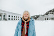 © bodnarphoto - Portrait of a joyful young girl in a warm winter jacket on a walk on a snowy street background, looking at the camera and smiling.