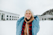 © bodnarphoto - Happy teen girl in warm clothes stands on a snowy street and looks at the camera with a smile on his face.