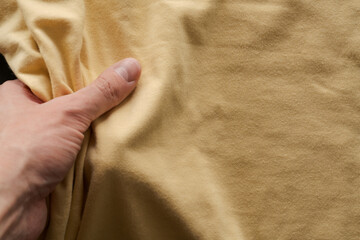 Wall Mural - top view man hand touching yellow cotton fabric