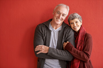 Poster - Love is longevity. Shot of an affectionate senior couple standing in front of a red background.