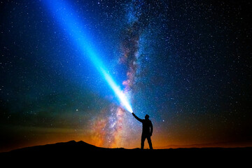 Man with flashlight pointed at the starry sky