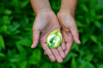 Wall Mural - hand embracing green leaf and globe, world earth day concept. green energy, esg concept. girlie hand