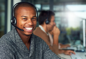 Poster - Let us search for the solutions you need. Portrait of a call centre agent working in an office with his colleagues in the background.