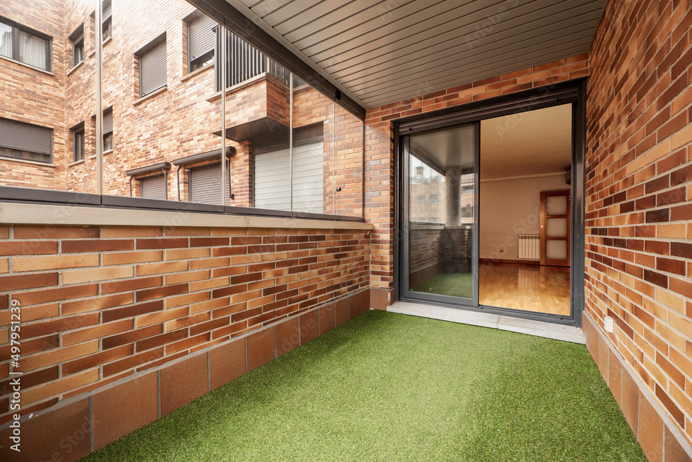 Enclosed terrace with glass and metal, brown bricks and green ...