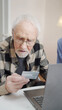 © iaginzburg - An elderly man learns to use a bank card for online shopping. He is taught by his young daughter