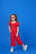 © oes - Portrait of surprised cute little toddler girl in the heart shape sunglasses. Child with open mouth having fun isolated over blue background. Looking at camera. Wow funny face