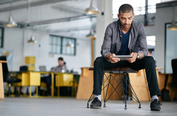 Poster - Hes a tech savvy young designer. Shot of a young man using a digital tablet while sitting in a modern office.