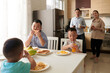 © DragonImages - Happy parents looking at their three sons ing breakfast at kitchen table