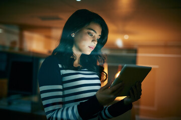 Wall Mural - Technology is the power tool that complements her skill set. Shot of a young businesswoman working late on a digital tablet in an office.