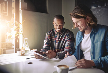 Canvas Print - Coffee fuels their creativity. Shot of two friends using a tablet while having coffee in a coffee shop.