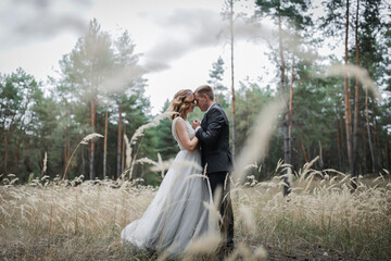 Wedding couple in the park. An elegant bride of European appearance and a groom in a black suit.