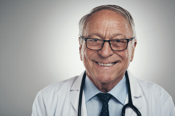 Wall Mural - Being the hospital favourite isnt an easy task. Shot of a happy elderly male doctor in the studio against a grey background.