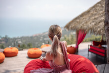 Woman In Pink Dress Lay Down On Orange Bean Bag On A Balcony Enjoy Highest Ocean View Point, Summer Vacation.