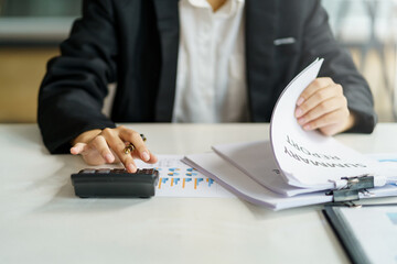 Wall Mural - Close-up of business woman hands using a calculator to check company finances and earnings and budget.