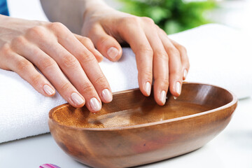 Wall Mural - Closeup female hands in wooden bowl with water