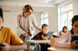 © Drazen - Senior teacher assists schoolgirl in using digital tablet during a class at school.